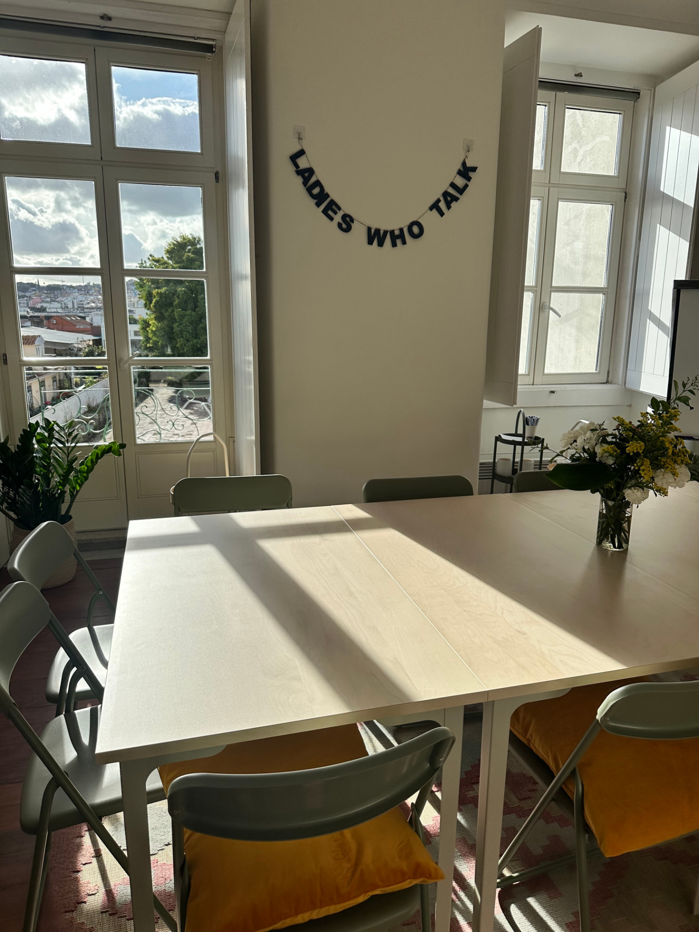 Bright Hub big room with the meeting table, Ladies Who Talk garland and the Lisbon view